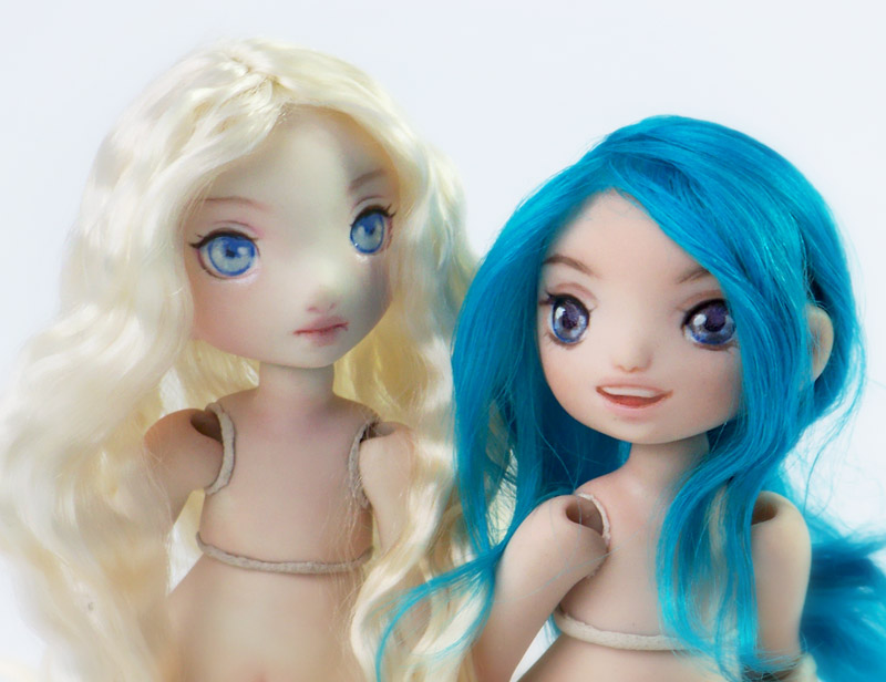 Two new porcelain bjd Meka dolls, one with platinum blonde hair and the other with electric blue hair.