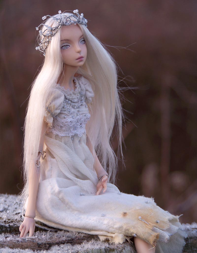 A porcelain doll sitting in frost.