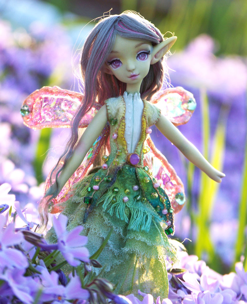 Green fairy doll standing in phlox flowers.