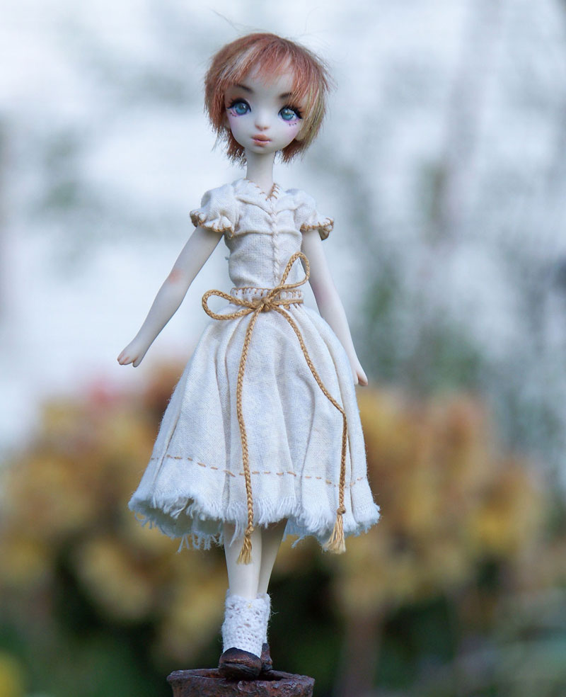China doll in rustic white cotton dress and short pixie haircut.