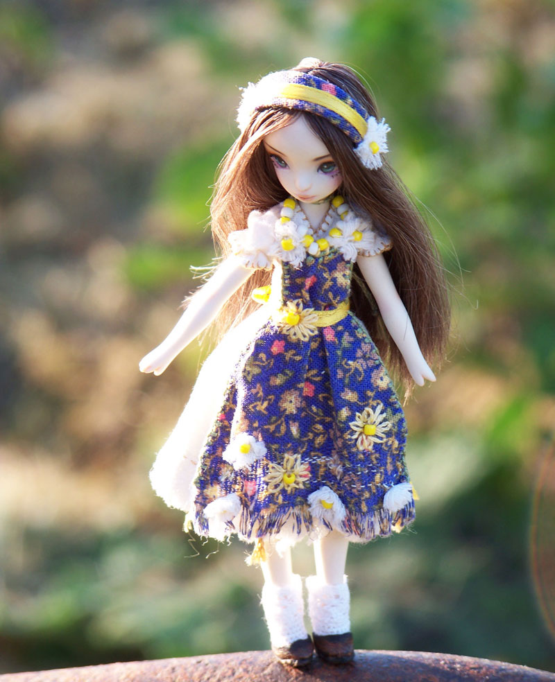 May Flowers doll standing in the garden, blue apron and flower headband on.